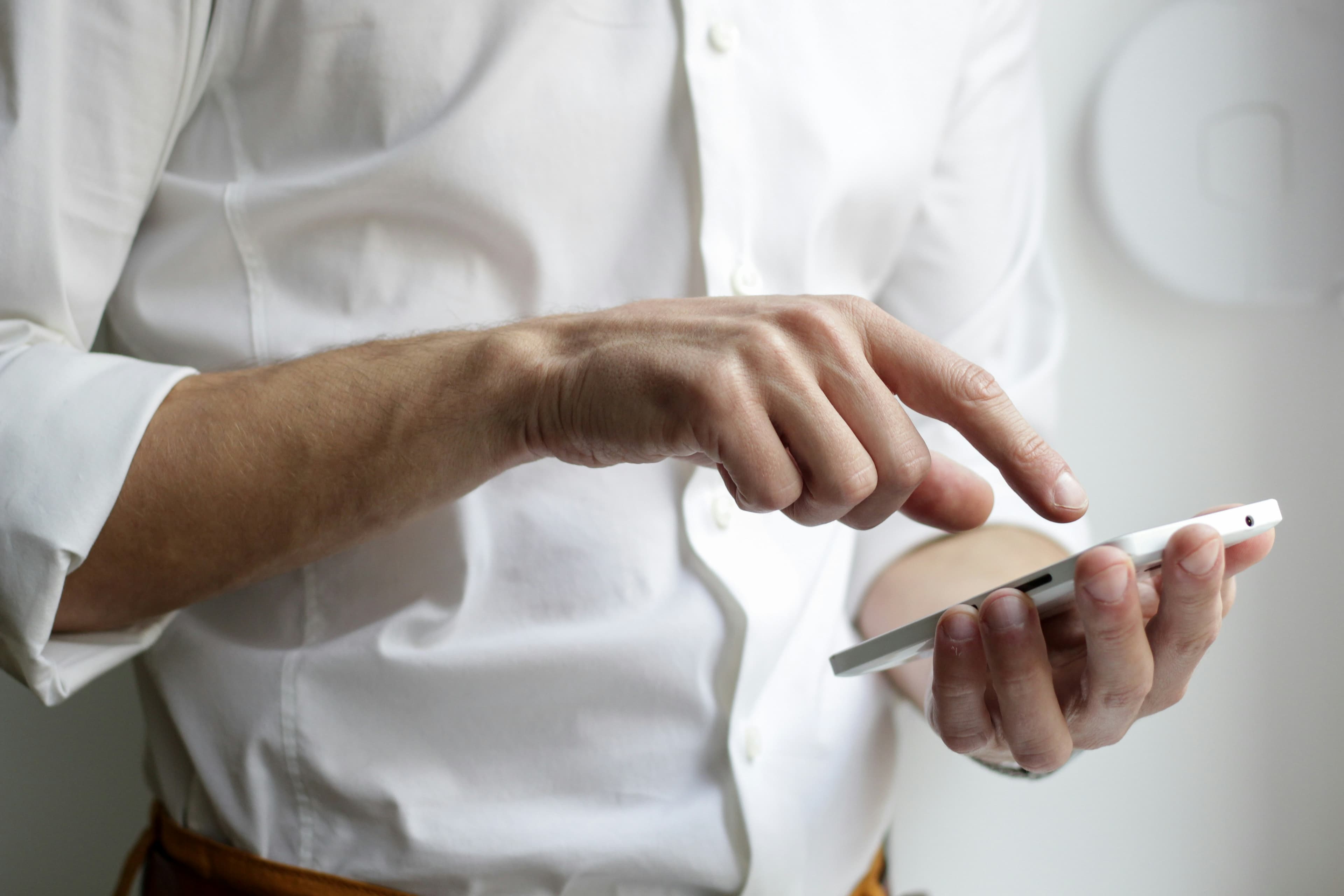 Close up of a person in a white shirt reading something on a handheld screen.